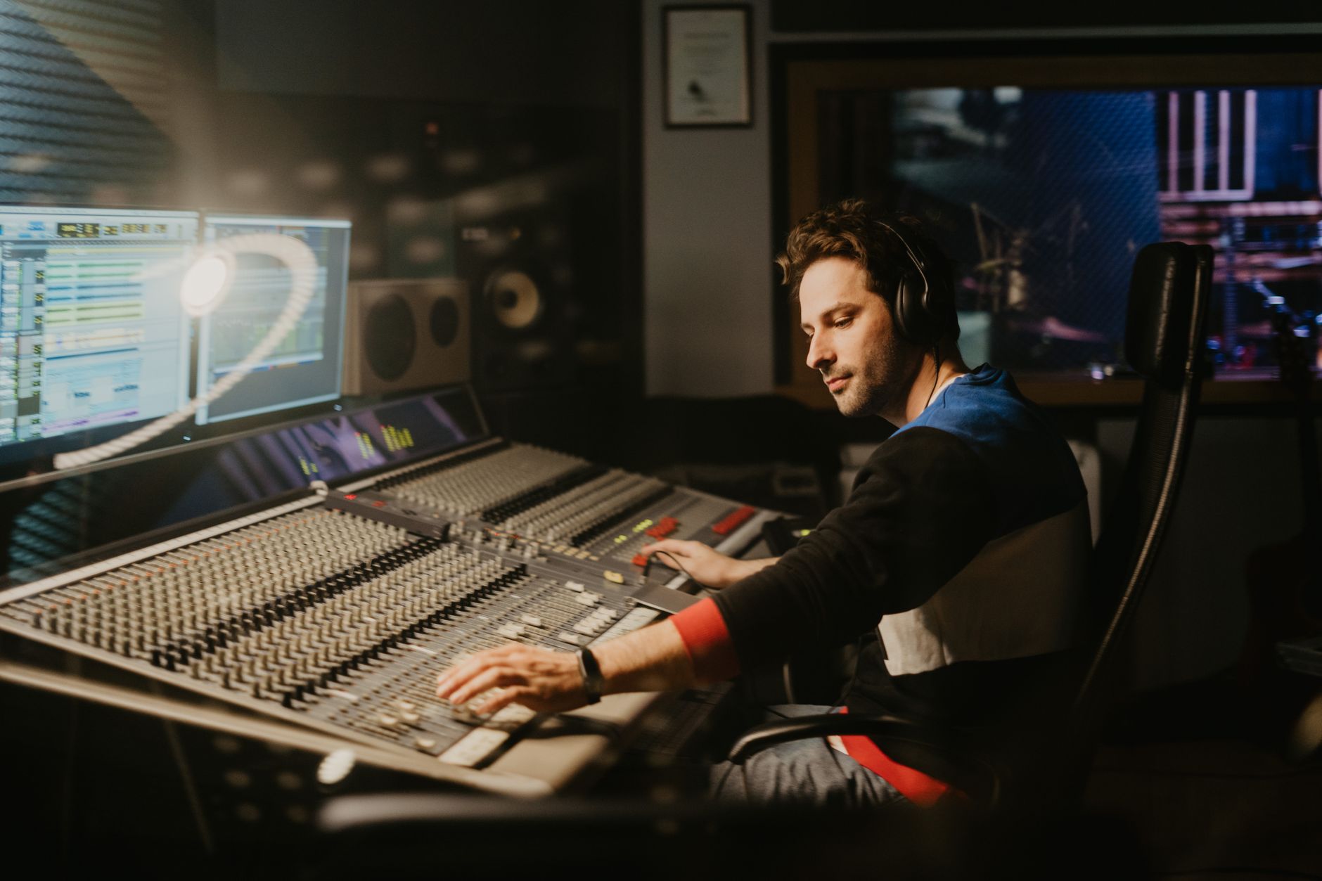Sound engineer at a mixing console in a professional music recording studio.