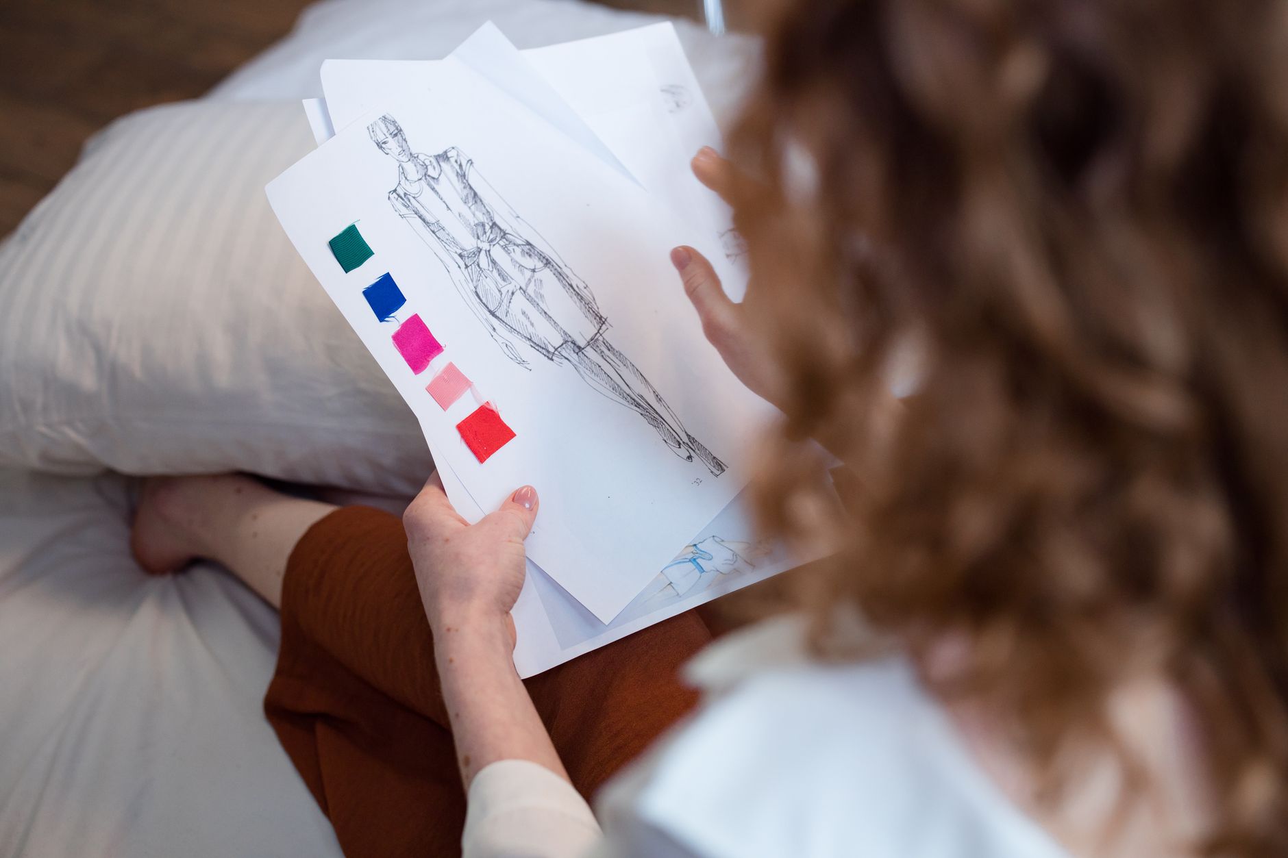 A fashion designer evaluating sketches and fabric samples, focusing on creative design.