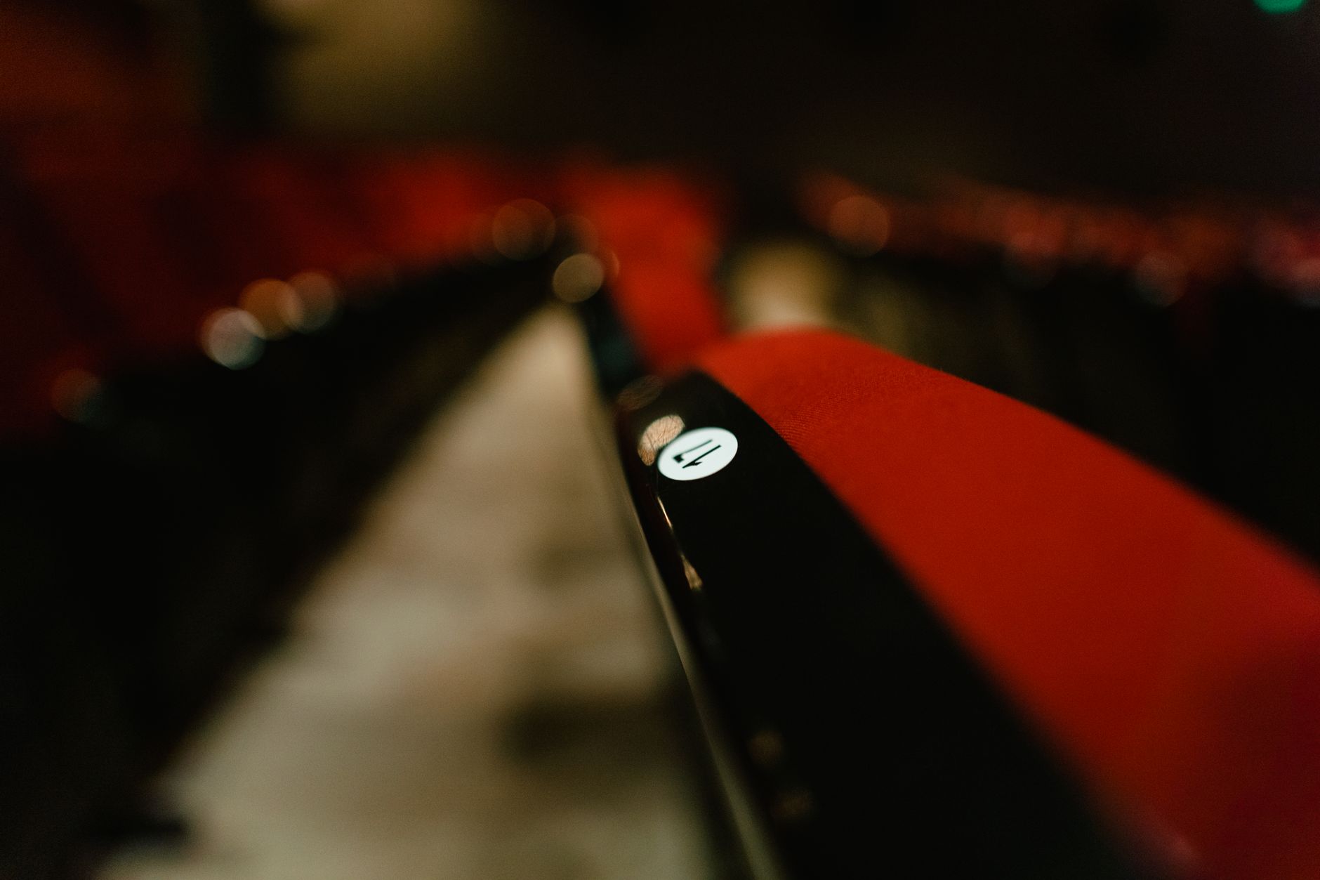 Dossier de fauteuil rouge avec un repère numéroté dans une salle de cinéma sombre, rangées de sièges floues au fond.